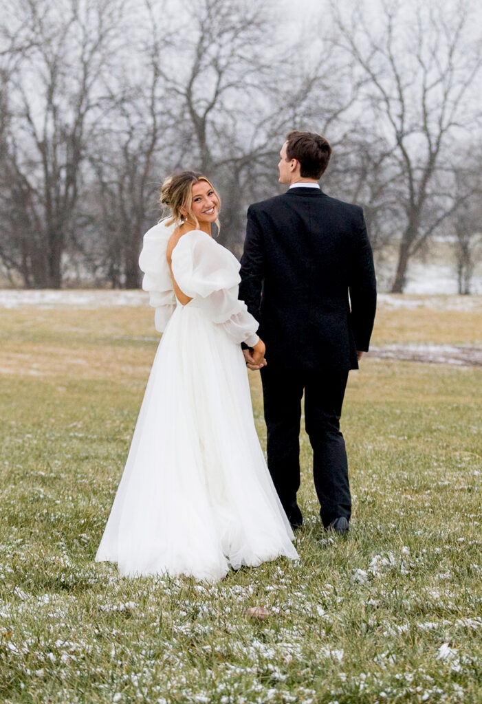 bride with groom in snow in a flowing gown with puffed long sleeves